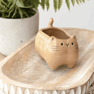 Cute cat-shaped ceramic creamer on wooden tray.